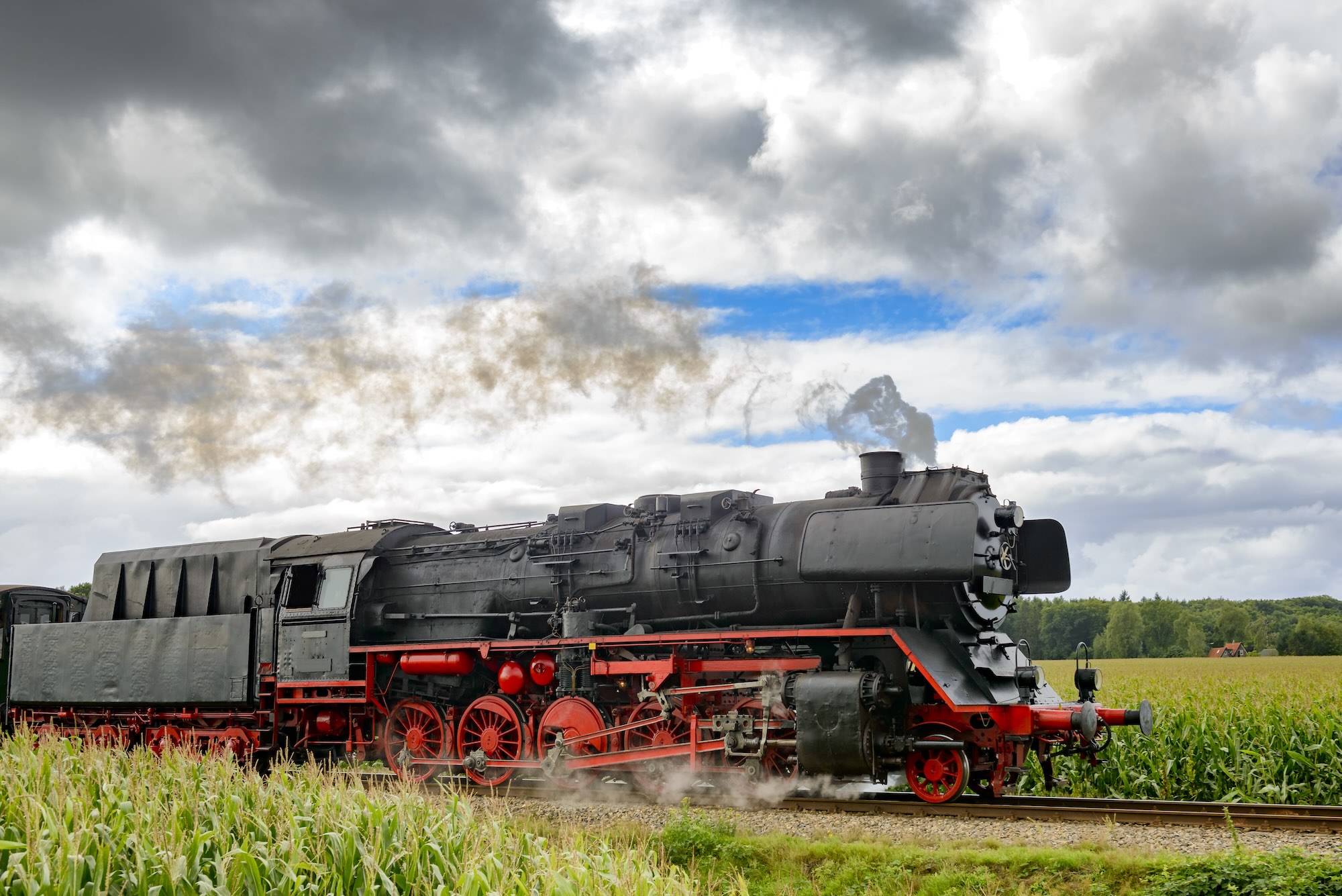 Old steam train pulling railway cars driving through the countryside. Stoomtrein